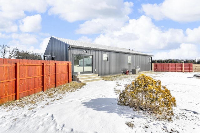 snow covered rear of property with central air condition unit