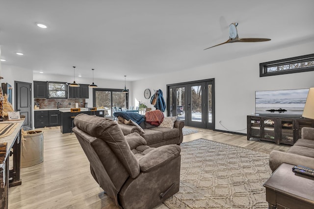 living room with french doors, ceiling fan, and light hardwood / wood-style floors