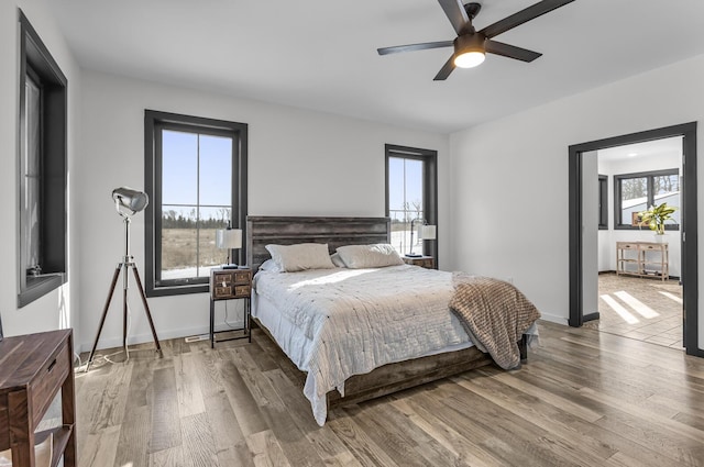 bedroom with multiple windows, hardwood / wood-style floors, and ceiling fan