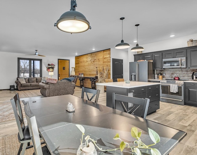 dining room featuring ceiling fan, light hardwood / wood-style floors, and wood walls