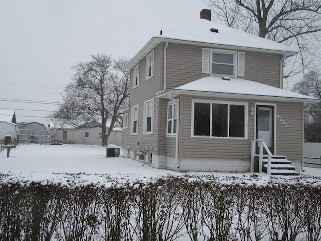 snow covered rear of property with central AC