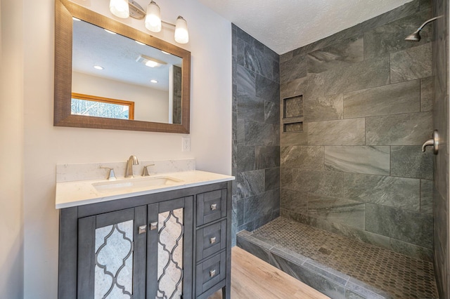 bathroom with vanity, a tile shower, and a textured ceiling