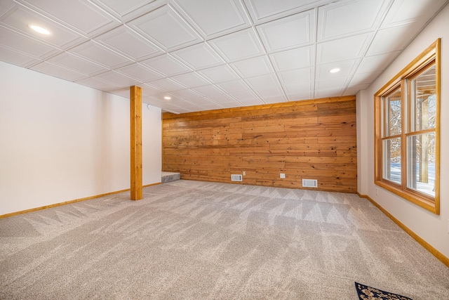 basement featuring carpet flooring and wood walls