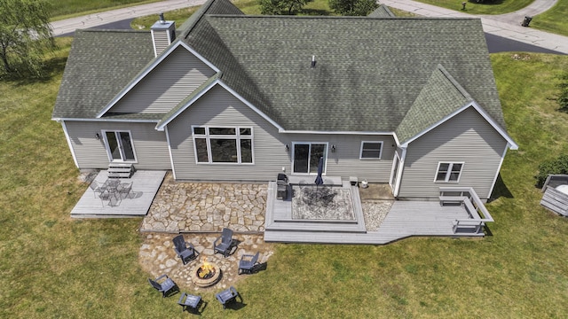 rear view of house with an outdoor fire pit, a deck, and a lawn