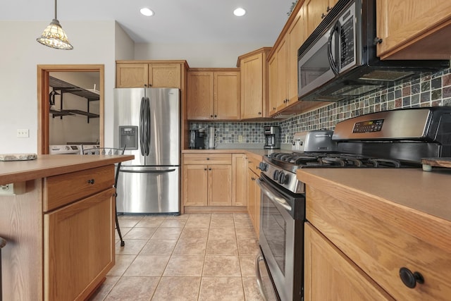 kitchen featuring tasteful backsplash, stainless steel appliances, light tile patterned floors, and pendant lighting