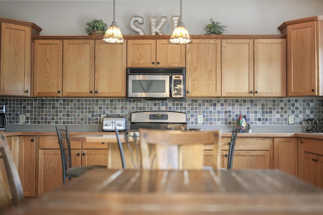 kitchen with backsplash, pendant lighting, and appliances with stainless steel finishes