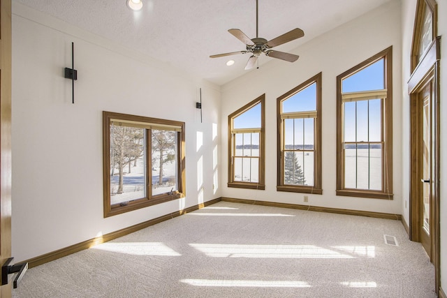 carpeted spare room featuring ceiling fan and a textured ceiling