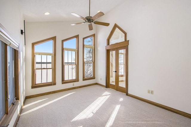 carpeted spare room with ceiling fan, high vaulted ceiling, and french doors