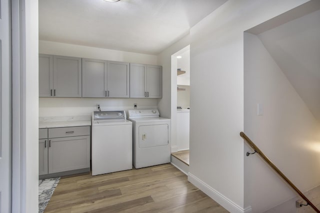 laundry area with light hardwood / wood-style flooring, independent washer and dryer, and cabinets