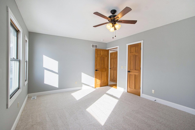 unfurnished bedroom with ceiling fan, light colored carpet, and multiple windows