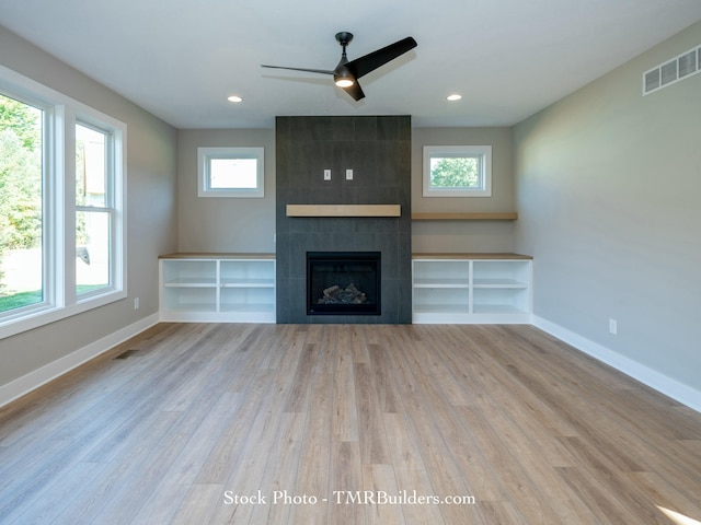 unfurnished living room with light wood-type flooring, ceiling fan, and a fireplace