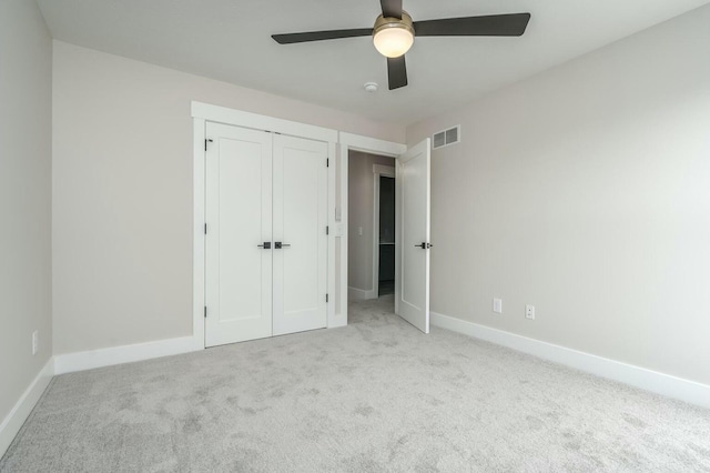 unfurnished bedroom with ceiling fan, light colored carpet, and a closet