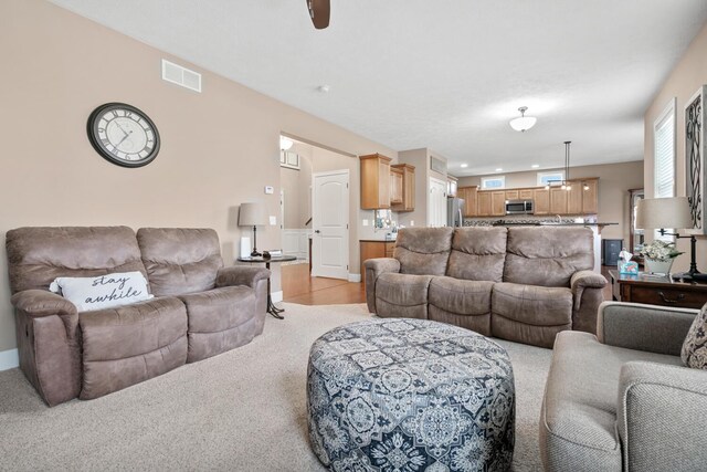 carpeted living room with ceiling fan