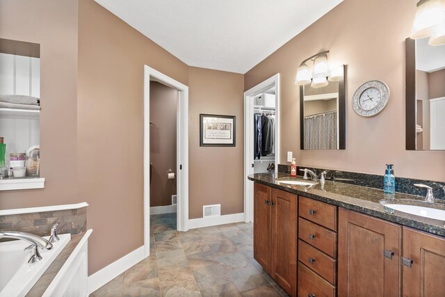 bathroom featuring vanity and tiled tub