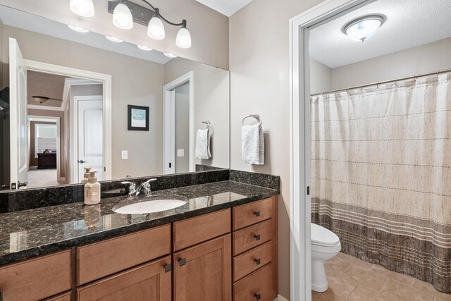 bathroom featuring tile patterned floors, a textured ceiling, toilet, and vanity