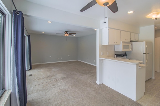 kitchen featuring ceiling fan, stove, kitchen peninsula, light carpet, and white cabinets