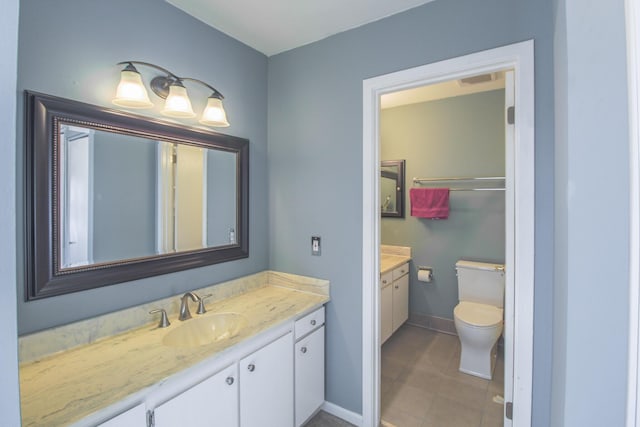 bathroom with toilet, vanity, and tile patterned flooring