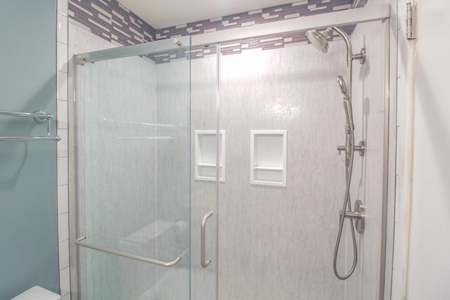 bathroom with a shower with shower door and toilet