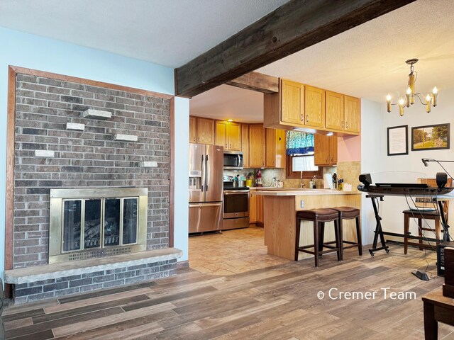 kitchen with pendant lighting, stainless steel appliances, kitchen peninsula, beam ceiling, and a breakfast bar area