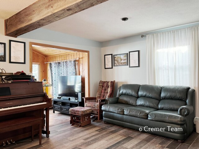 living room featuring beam ceiling, hardwood / wood-style flooring, and wooden walls