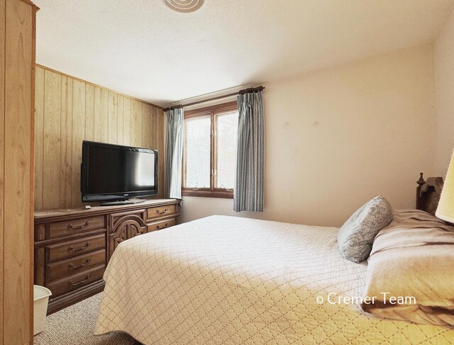 carpeted bedroom featuring wooden walls