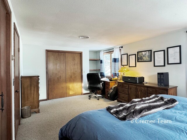 bedroom with light colored carpet and a textured ceiling