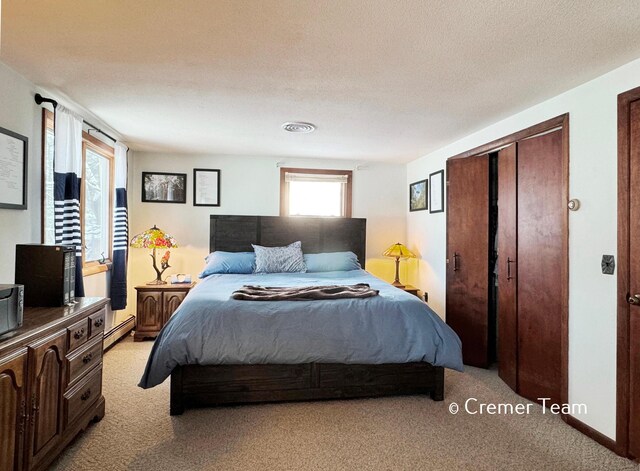 carpeted bedroom with a baseboard radiator, multiple windows, and a closet