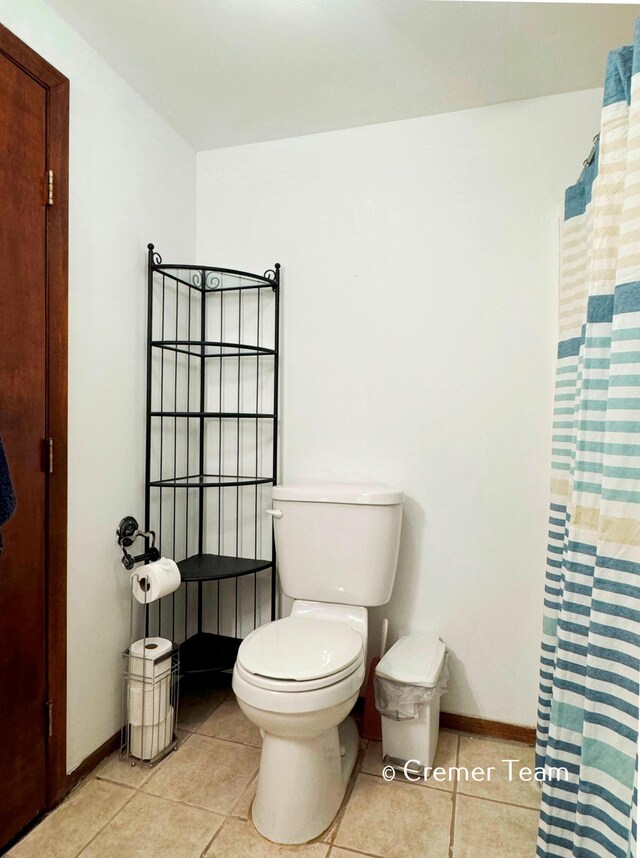 bathroom featuring curtained shower, toilet, and tile patterned floors