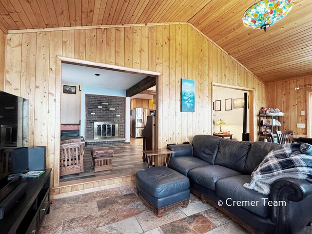 living room featuring a fireplace, wooden ceiling, vaulted ceiling, and wood walls