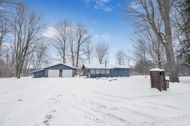 snowy yard featuring a garage and an outdoor structure