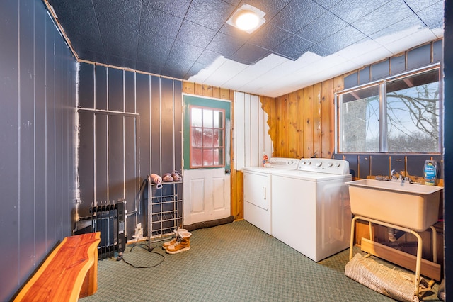 laundry area featuring a wealth of natural light, independent washer and dryer, wood walls, and sink