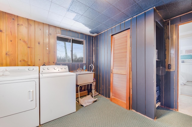 laundry area featuring carpet floors, sink, independent washer and dryer, and wood walls