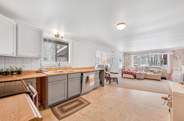 kitchen with light colored carpet, gray cabinetry, dishwasher, and sink