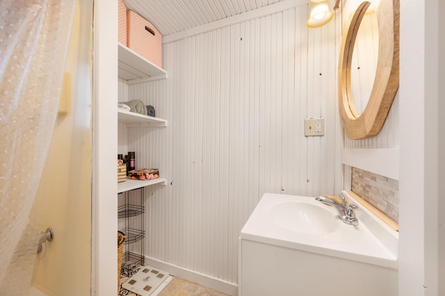 bathroom featuring tile patterned flooring, wood walls, and vanity