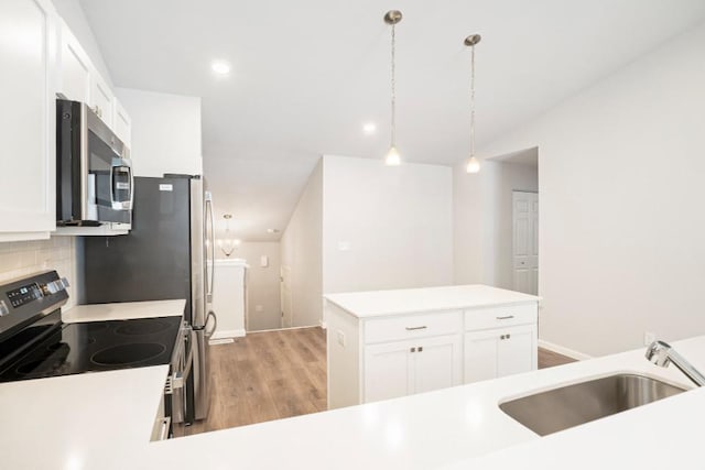 kitchen featuring appliances with stainless steel finishes, pendant lighting, tasteful backsplash, white cabinetry, and sink