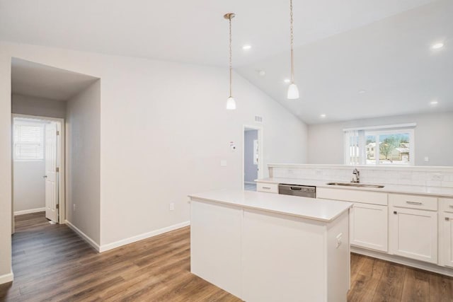 kitchen with lofted ceiling, sink, white cabinetry, decorative light fixtures, and a center island