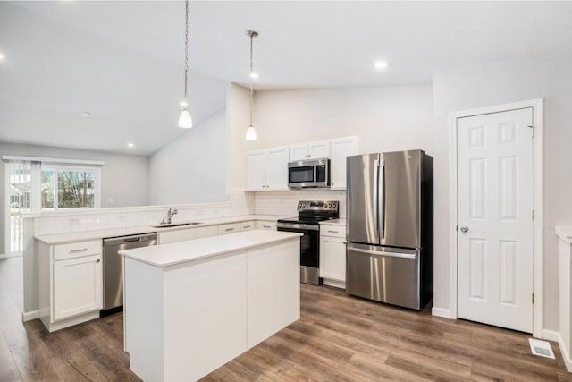 kitchen featuring pendant lighting, sink, appliances with stainless steel finishes, a center island, and white cabinets