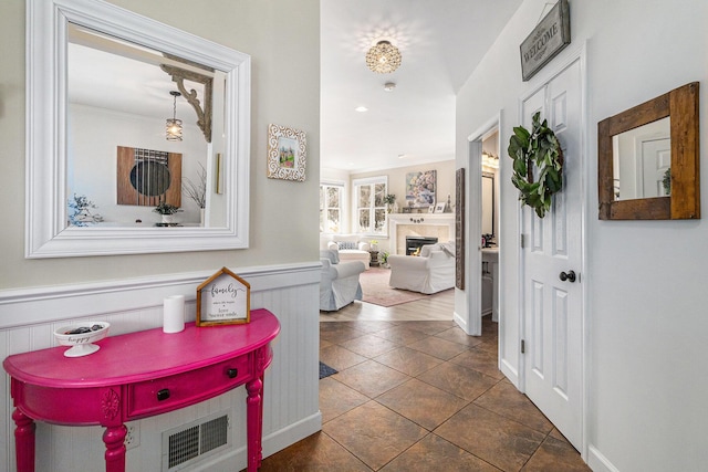 foyer with dark tile patterned flooring and crown molding