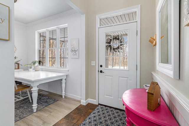 entrance foyer with a healthy amount of sunlight, wood-type flooring, and ornamental molding