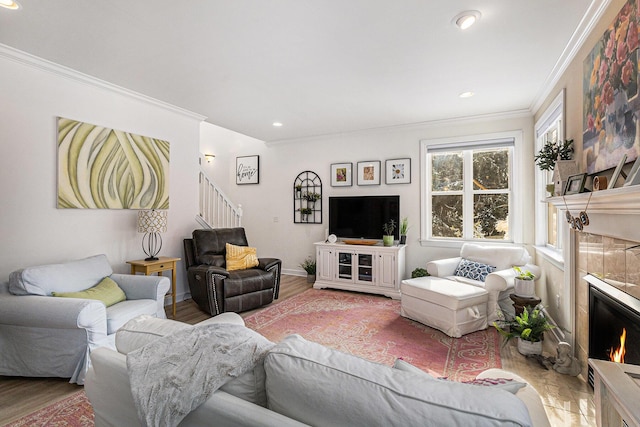 living room featuring wood-type flooring, a tile fireplace, and ornamental molding