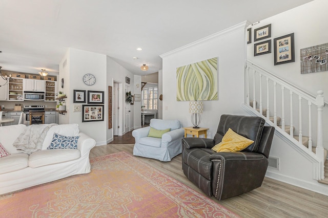 living room with ornamental molding, light hardwood / wood-style floors, and a chandelier