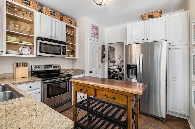 kitchen featuring appliances with stainless steel finishes, sink, light stone counters, and white cabinetry