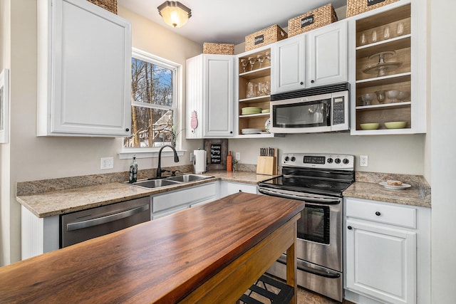 kitchen featuring white cabinets, appliances with stainless steel finishes, sink, and light stone counters