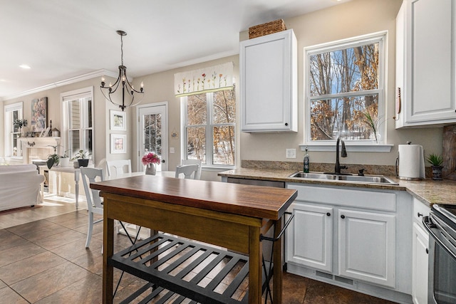 kitchen featuring sink, an inviting chandelier, hanging light fixtures, stainless steel range, and white cabinets