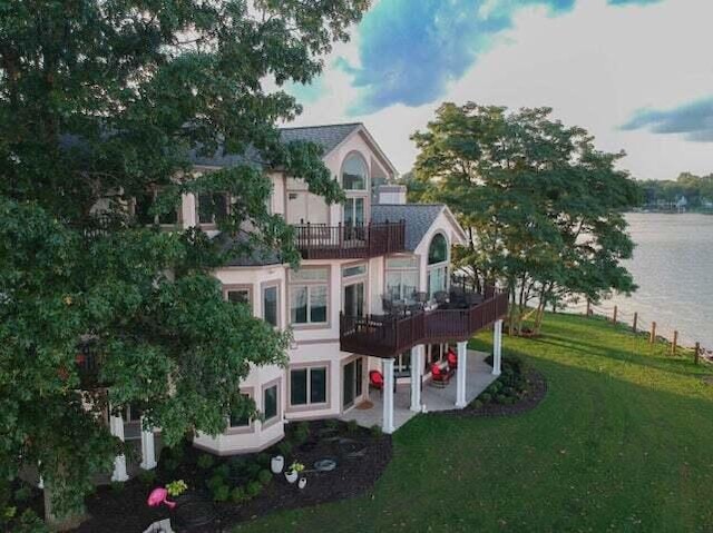 rear view of property with a water view, a yard, a balcony, and a patio