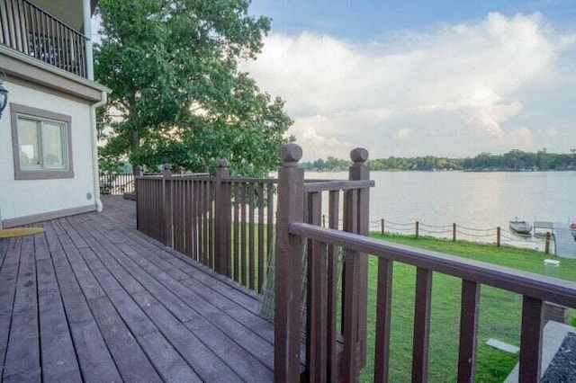 wooden deck with a water view and a lawn