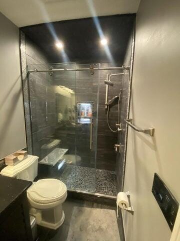 bathroom with a shower with shower door, toilet, and vanity