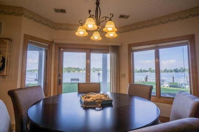 dining area featuring a water view and an inviting chandelier