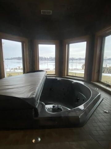 interior space with a water view and a hot tub