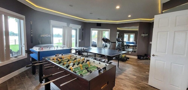 game room featuring a wealth of natural light, ornamental molding, and hardwood / wood-style floors